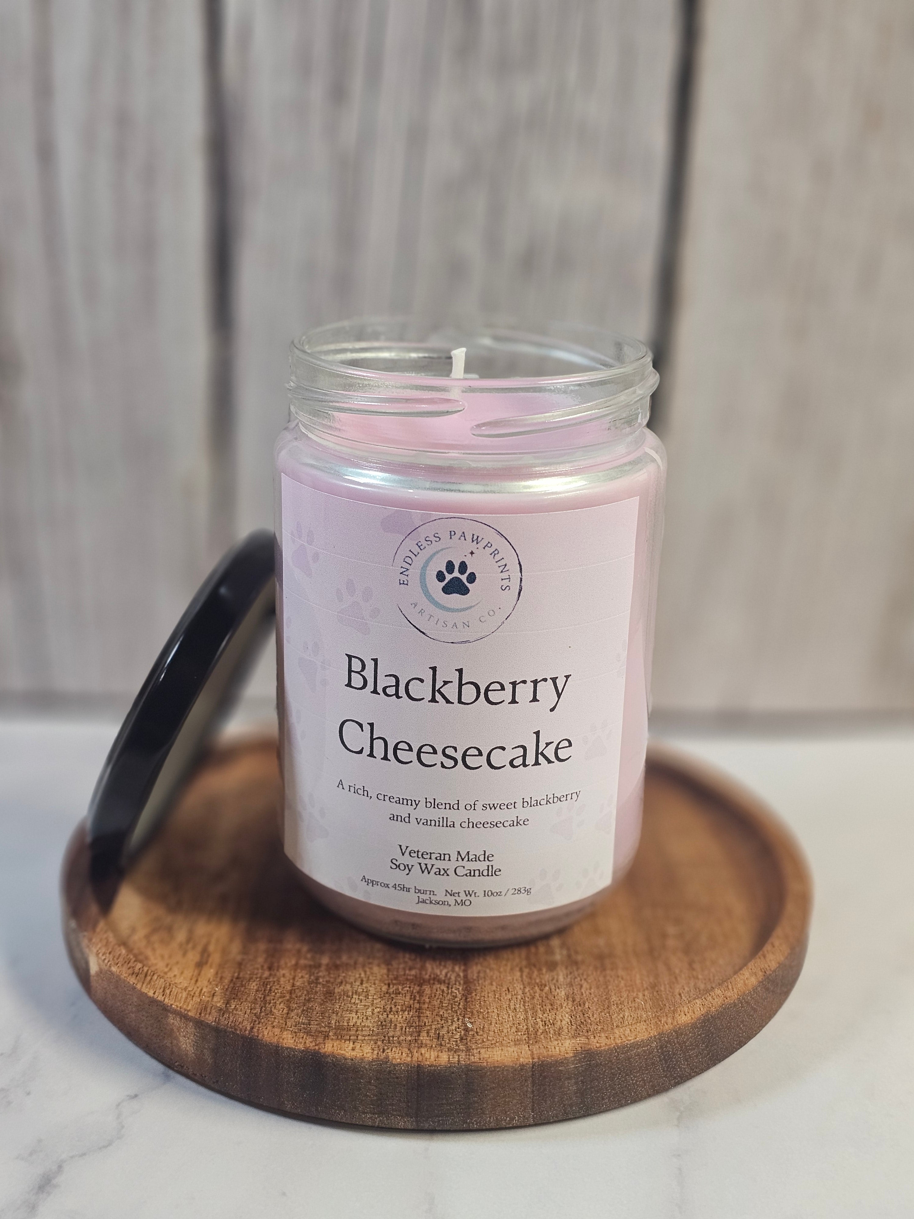 Jar of 'Blackberry Cheesecake' candle on a wooden coaster with a neutral background