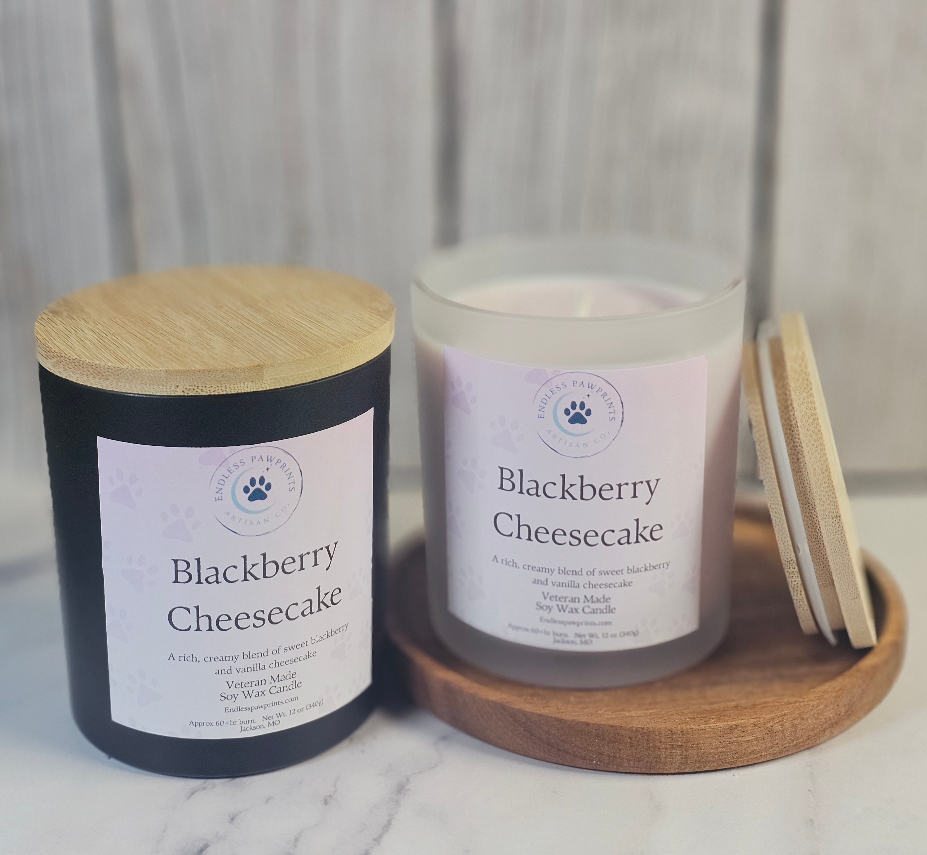 Two candles labeled 'Blackberry Cheesecake' on a wooden tray with a neutral background