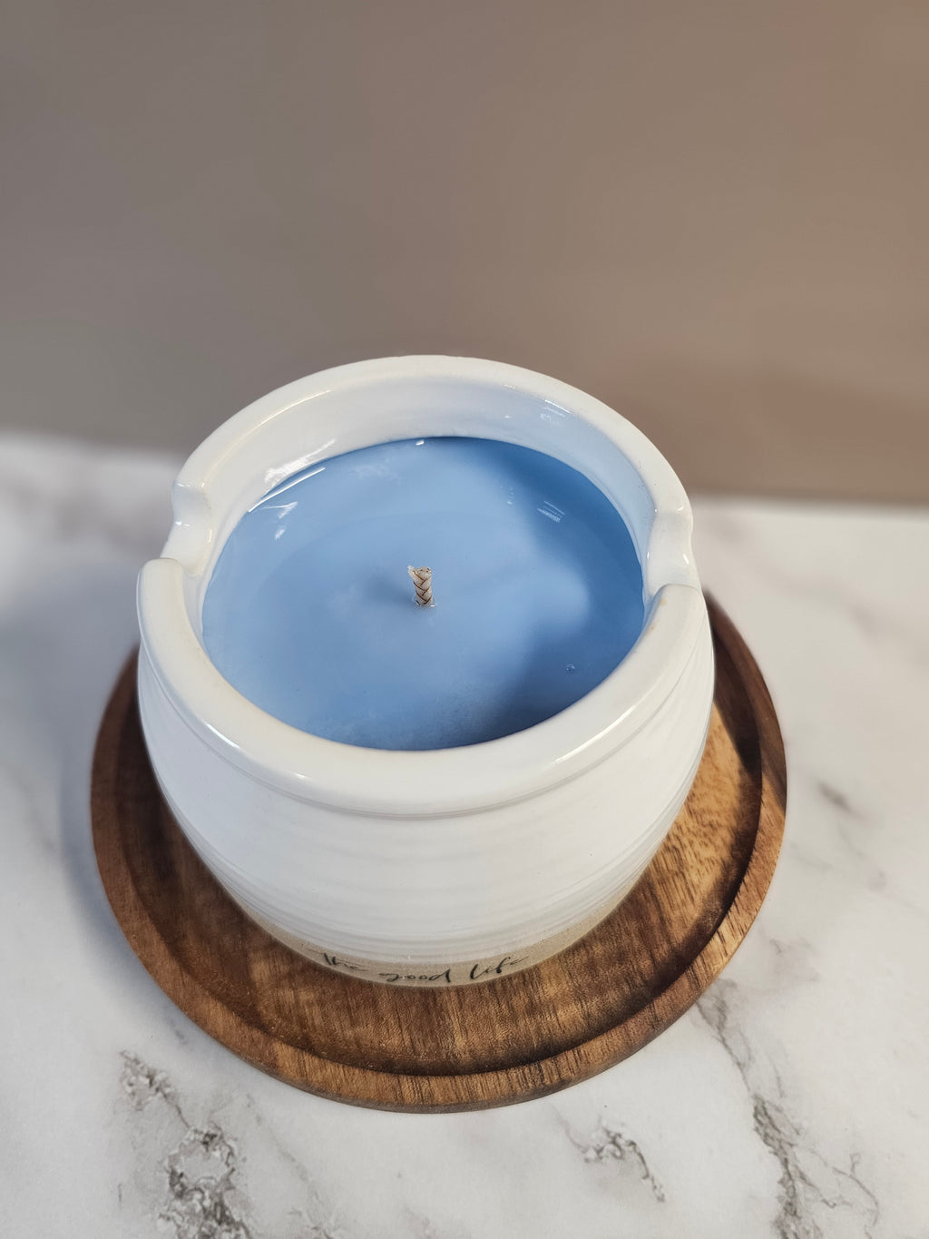 Candle with a wooden lid on a marble surface