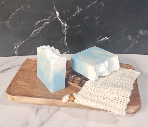 Two bars of soap on a wooden board with a marble background