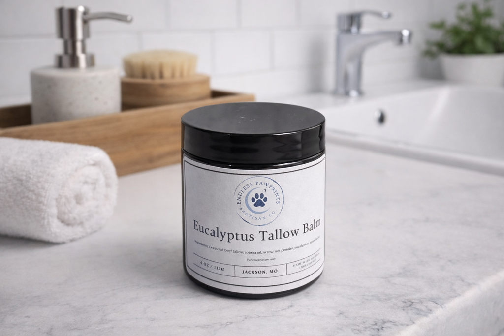 Jar of Eucalyptus Tallow Balm on a bathroom counter with a sink and towel in the background.