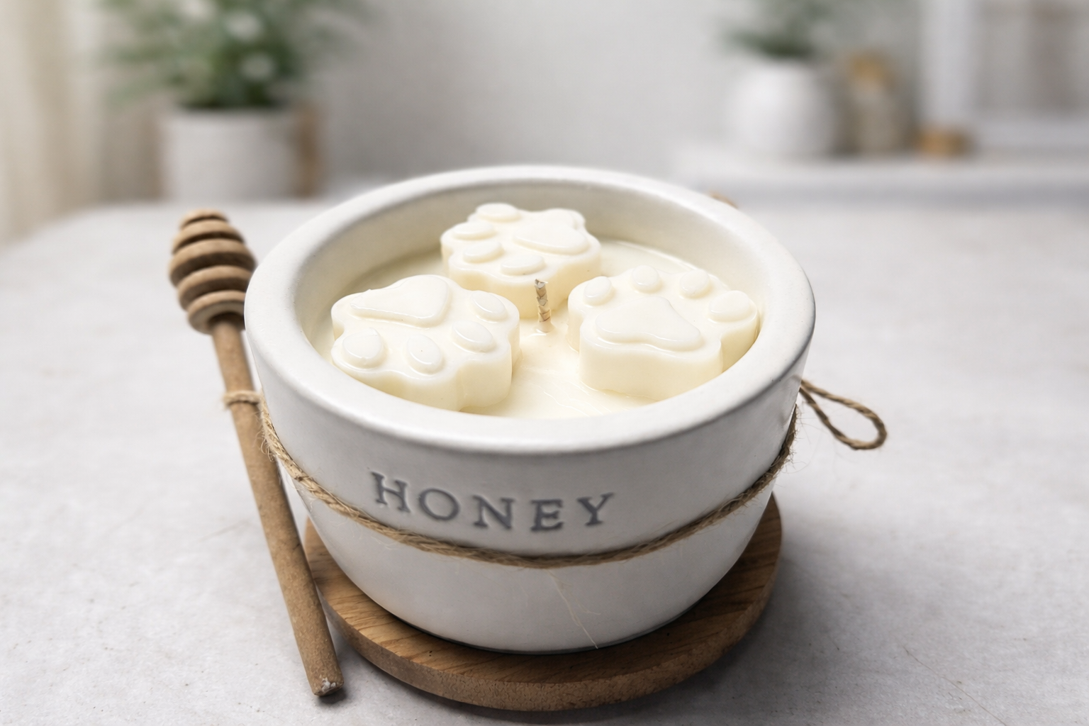 White Honey pot candle sitting on a counter top with a wooded lid and honey stir stick.