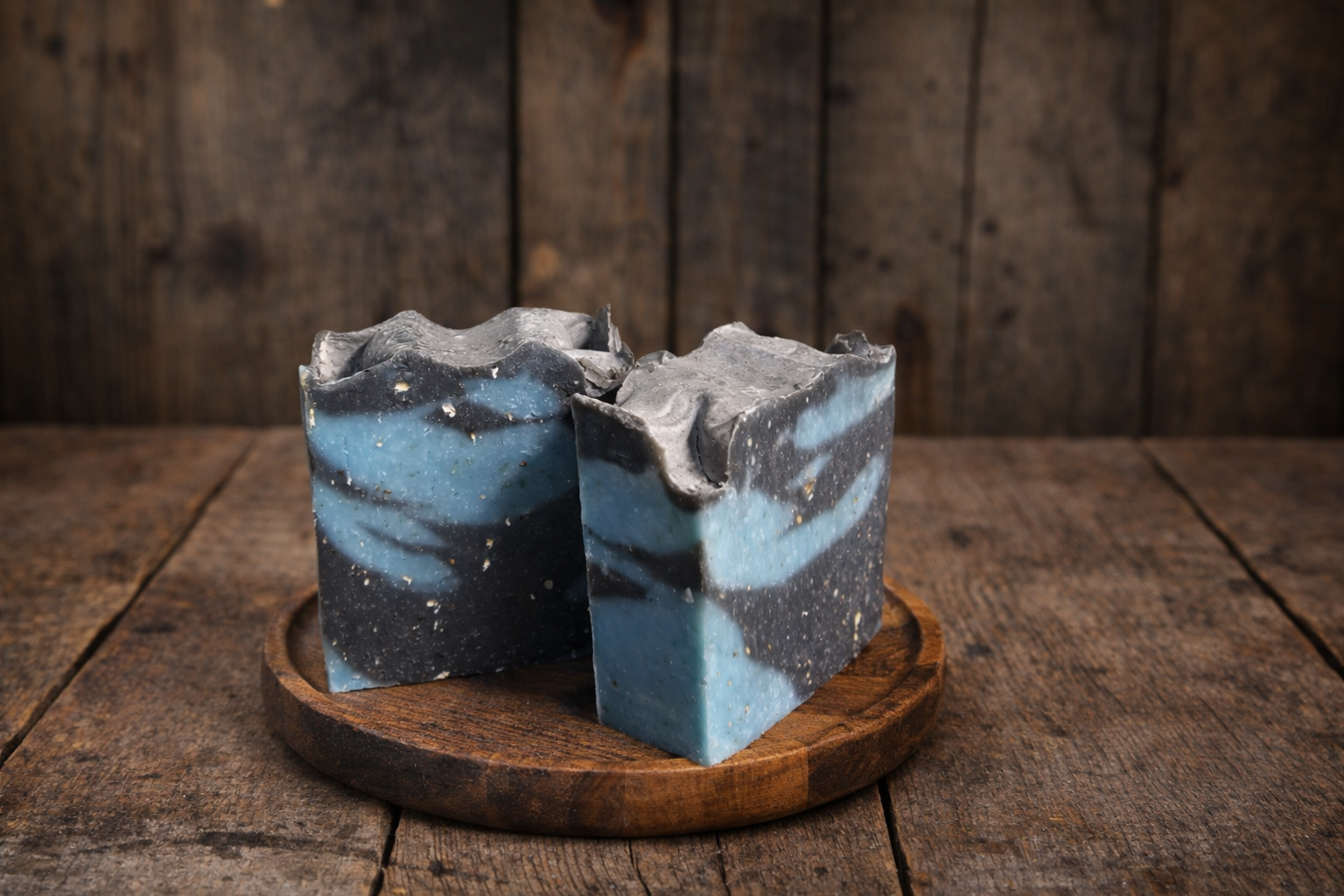 Two layered blue and gray soap bars on a wooden stand against a rustic wooden background