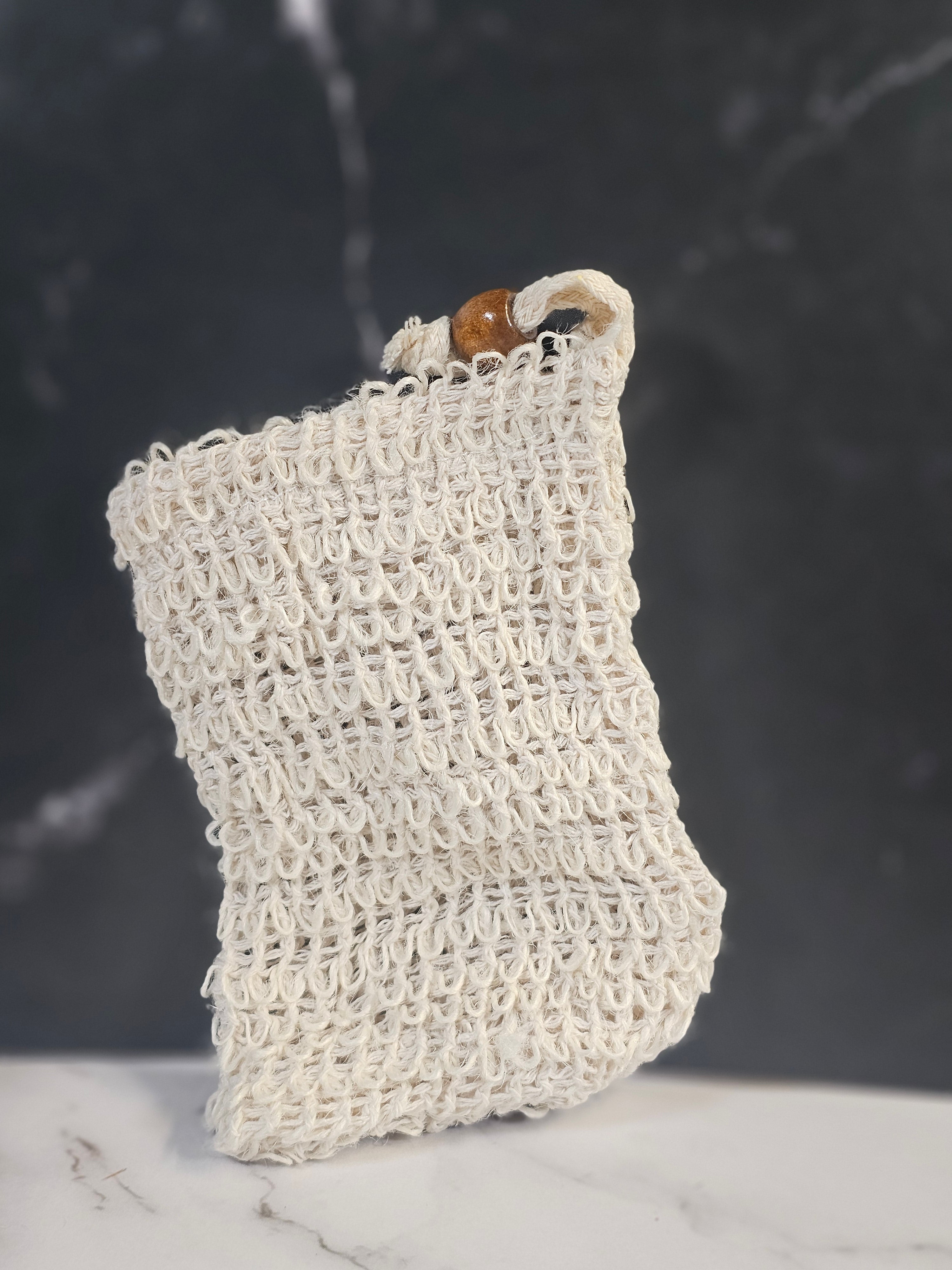 White woven soap saver bag on a dark background