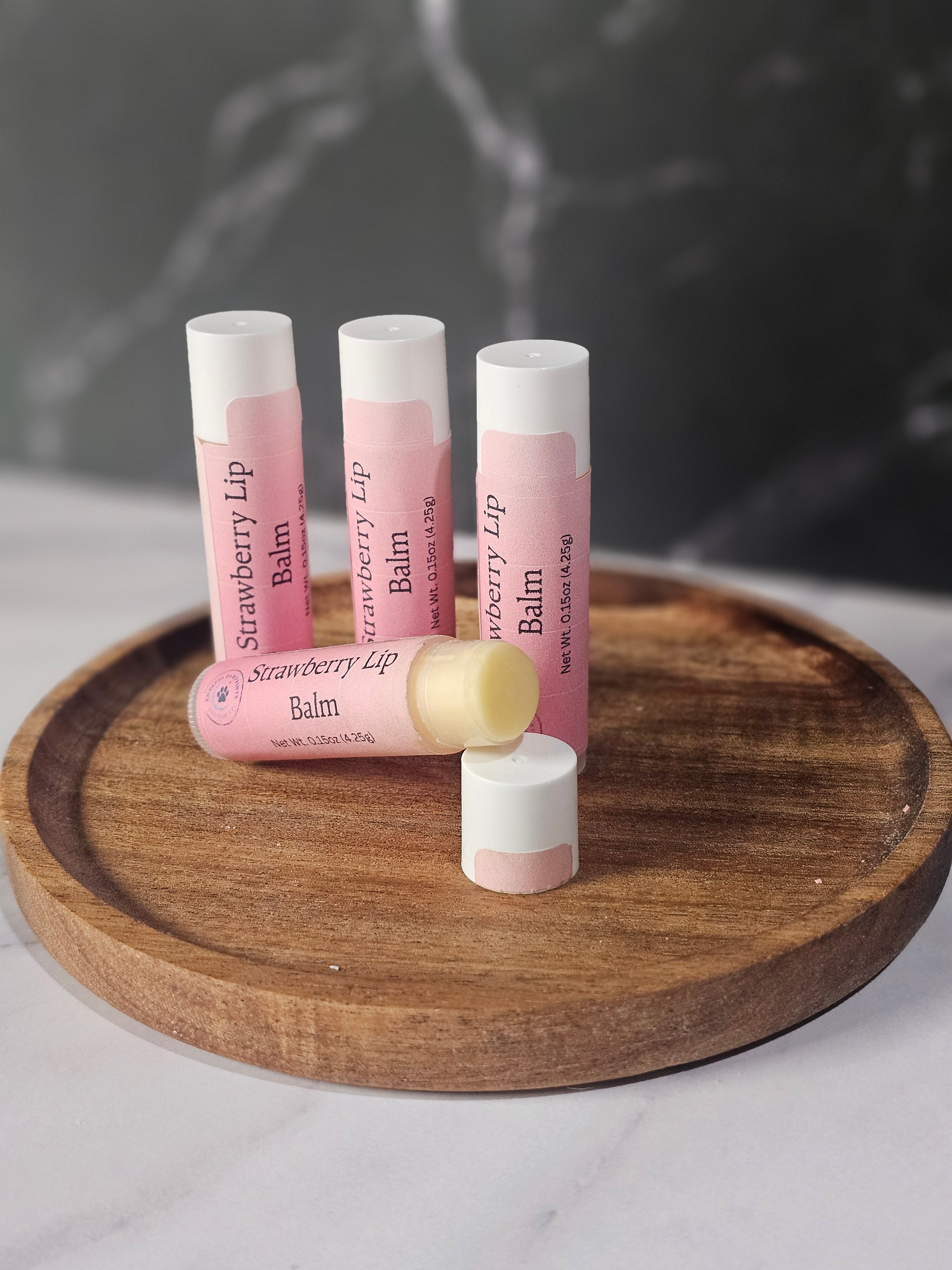 Three lip balms on a wooden stand with a dark background