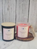 Two Strawberry Vanilla candles on a wooden surface with a marble background