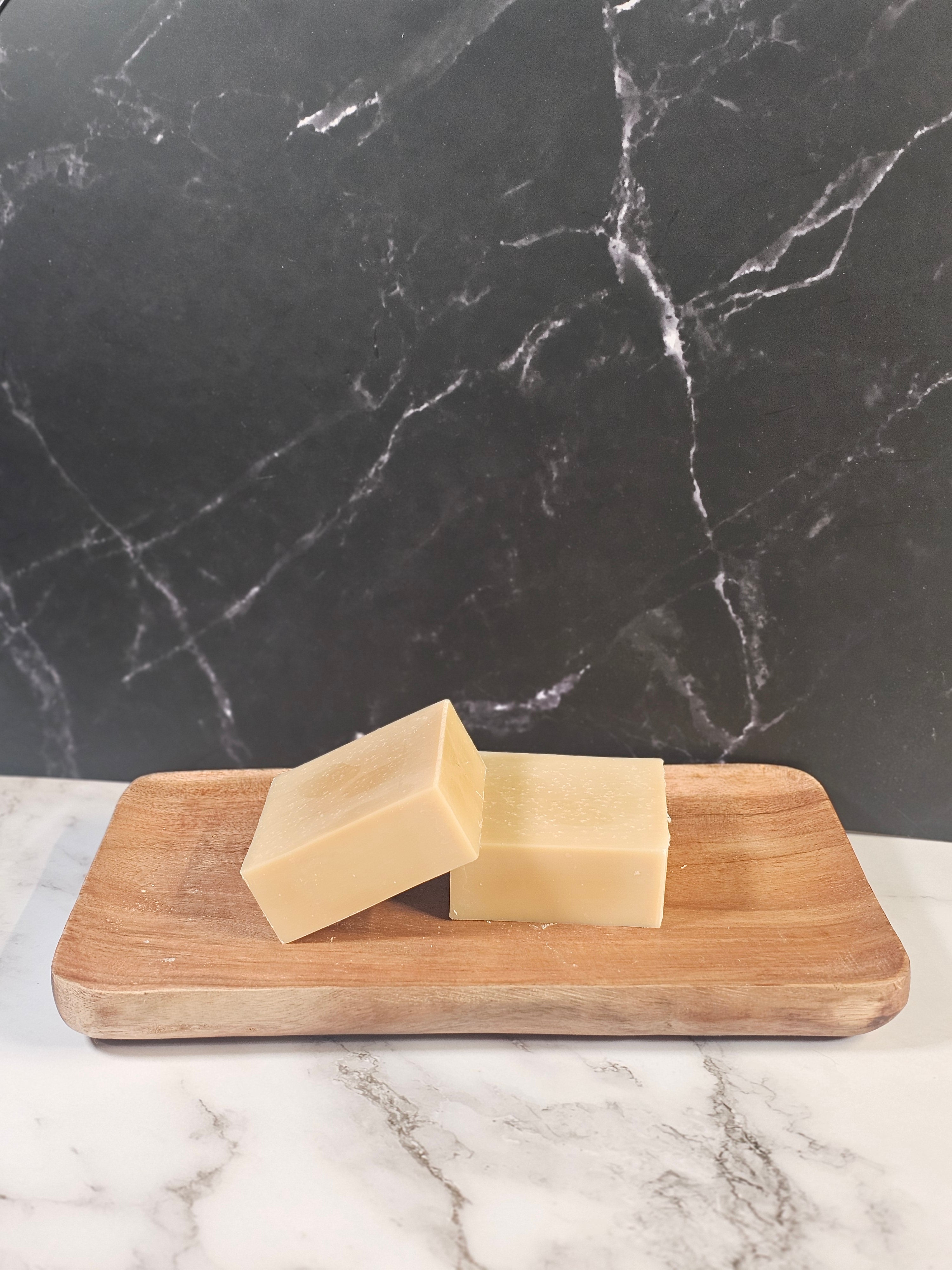 Wooden tray with two bars of soap on a marble surface