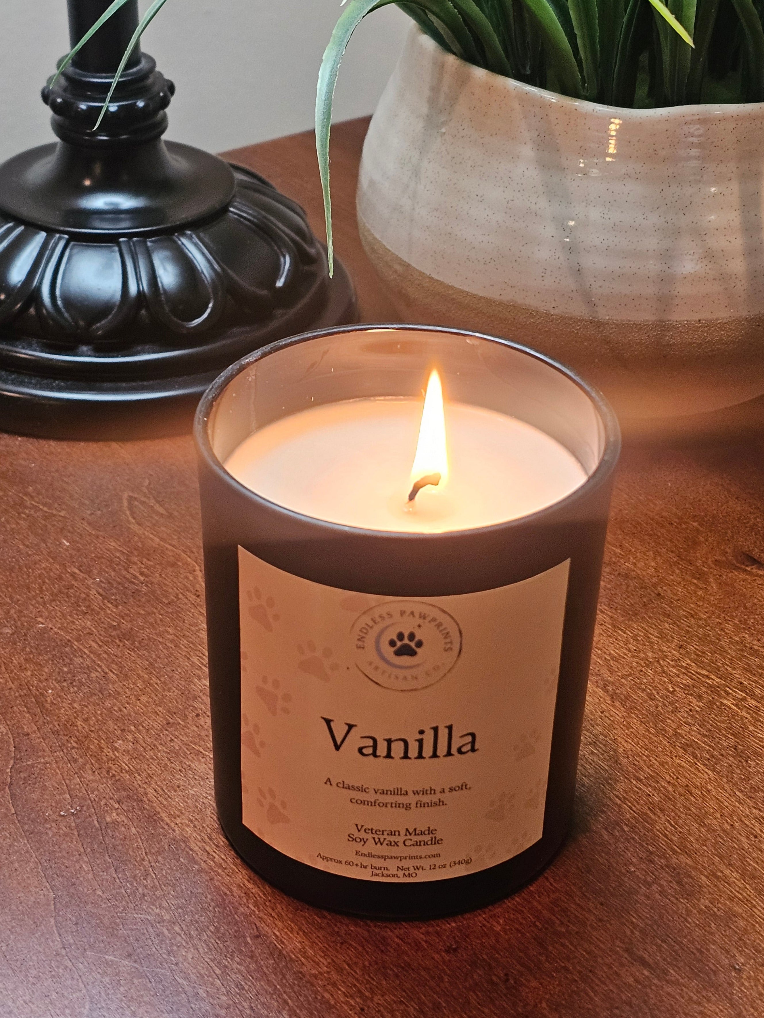 Vanilla candle siting on end table in front of a plant and lamp