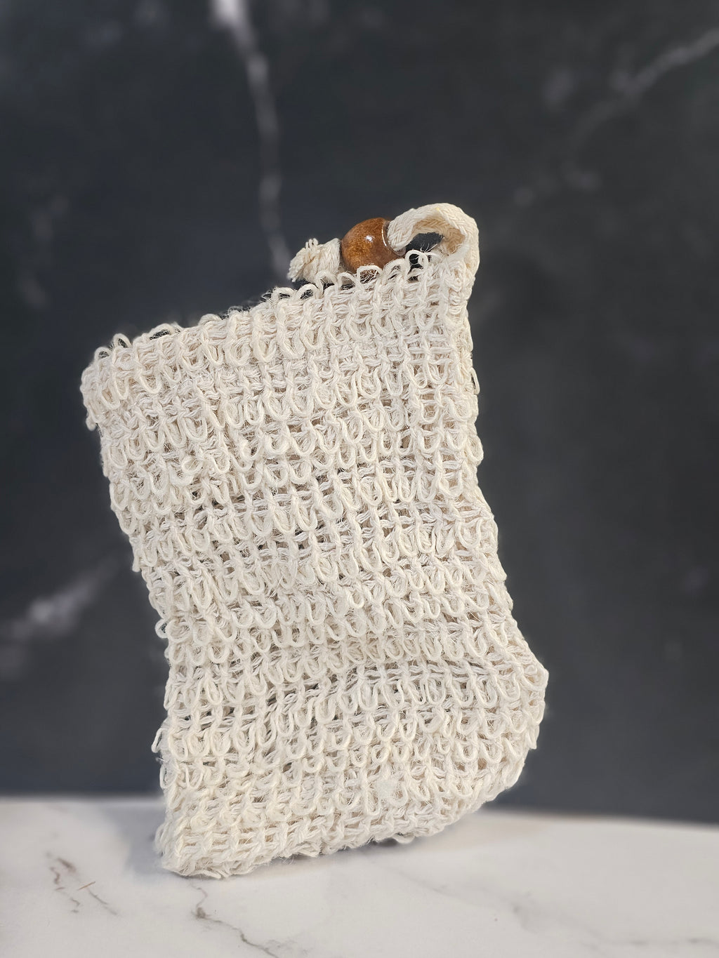 White soap saver bag on a black marble background