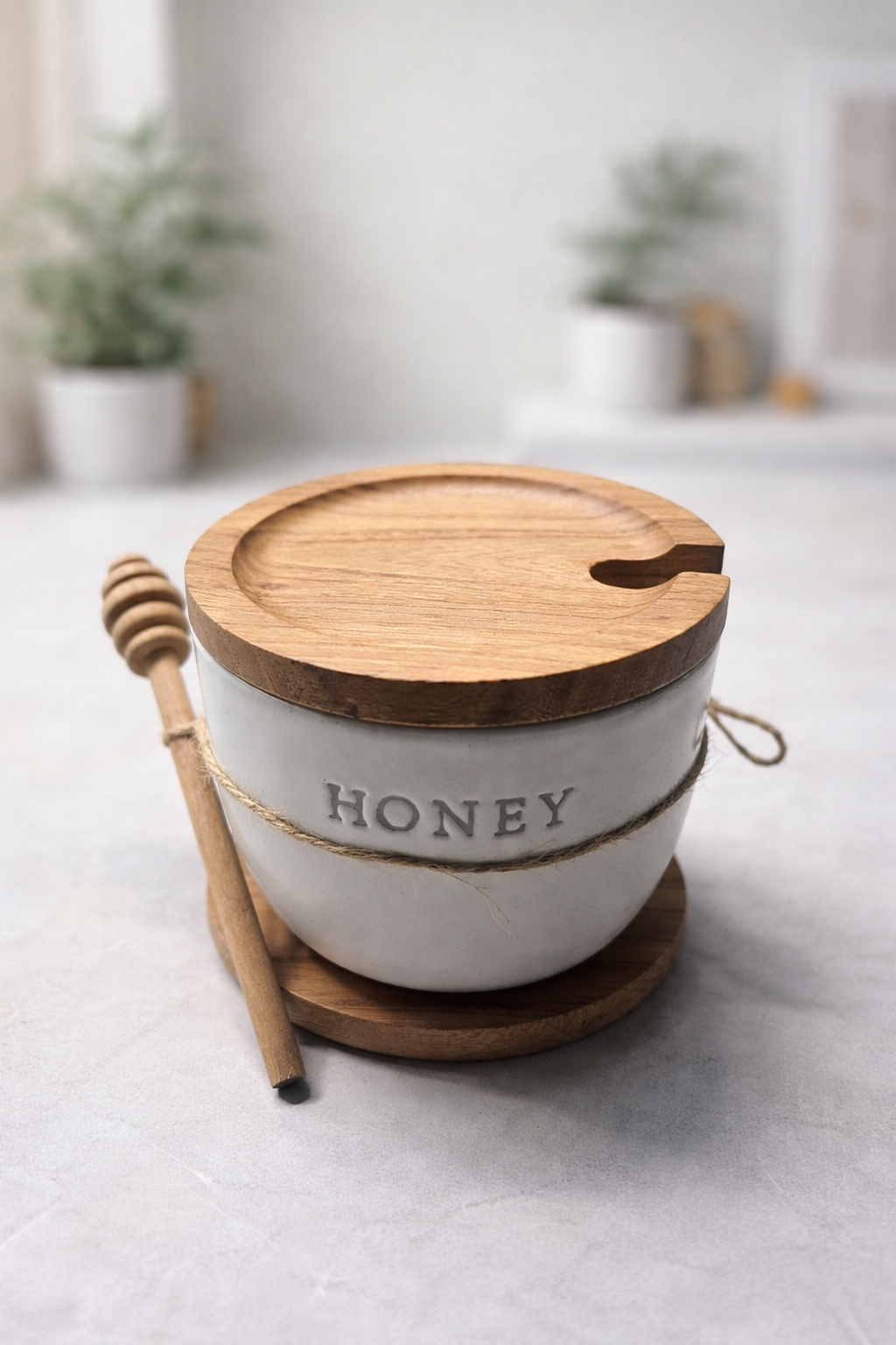 Honey container with wooden lid and honey dipper on a light surface